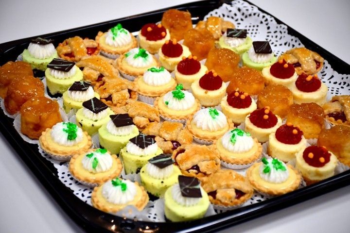 A black tray filled with a variety of pastries and cupcakes
