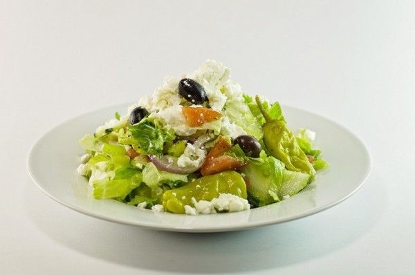 A white plate topped with a salad of vegetables and cheese.