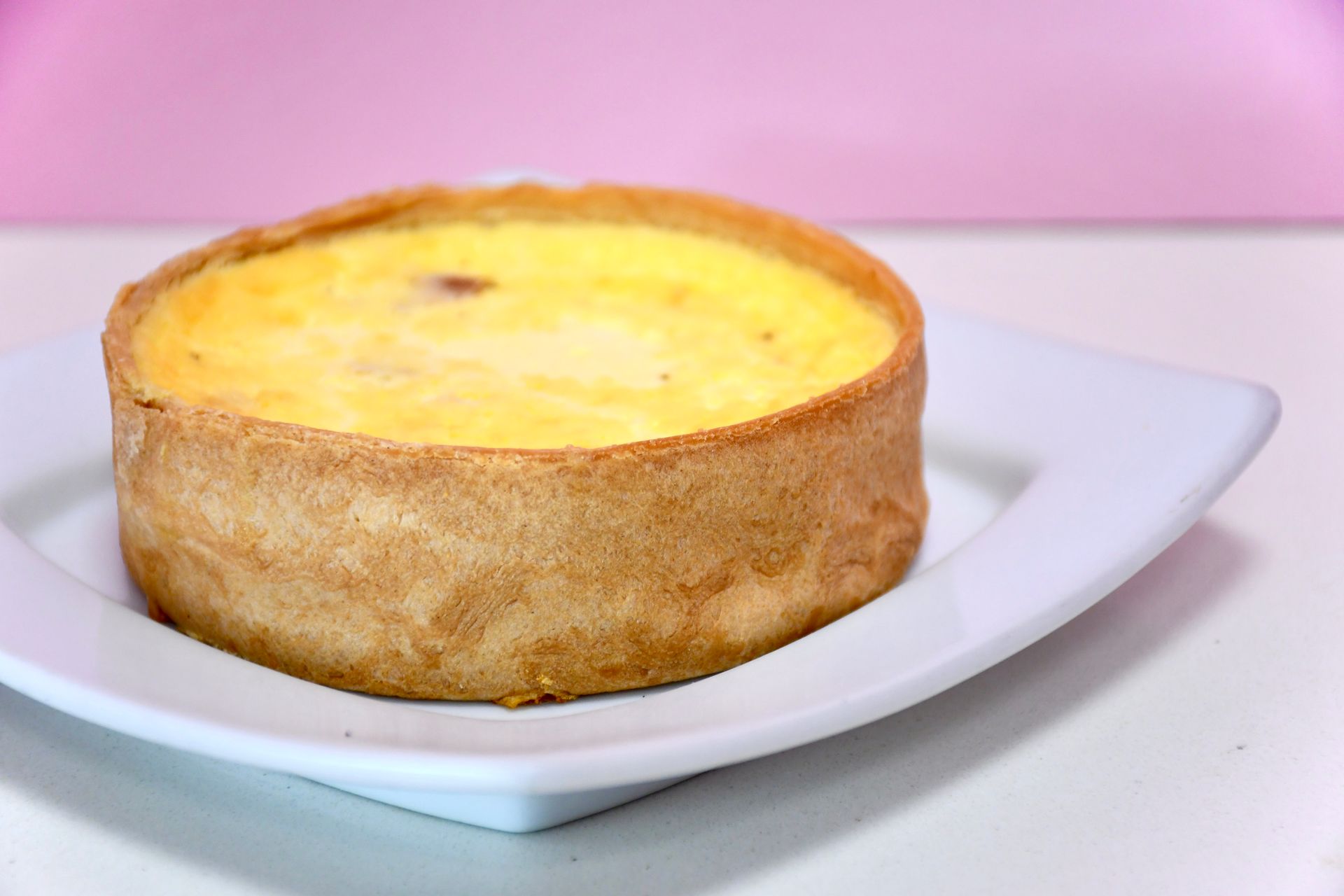 A pie is sitting on a white plate on a table.