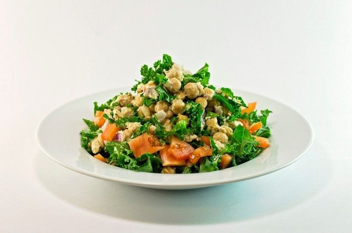 A white plate topped with a salad of chickpeas , tomatoes , and kale.