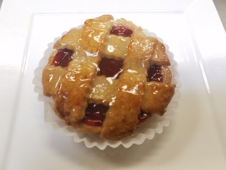 A cherry pie in a paper wrapper on a white plate