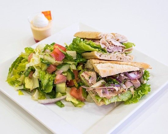 A white plate topped with a sandwich and a salad.