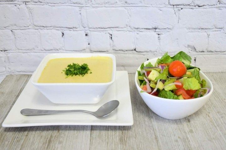 A bowl of soup and a bowl of salad are on a table.