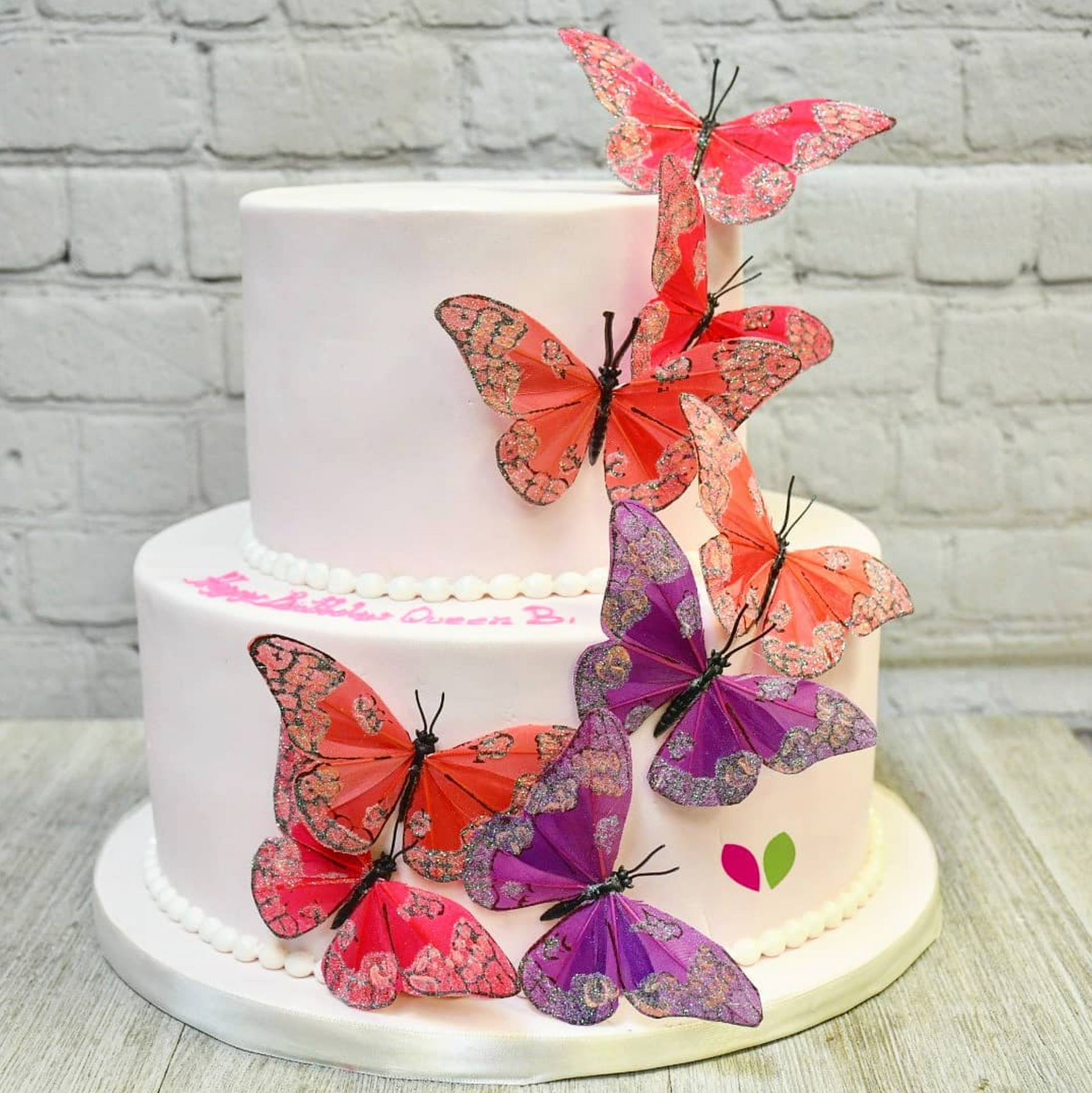 A white cake with pink and purple butterflies on it