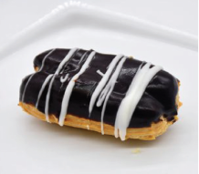 A chocolate eclair with white icing on a white plate.