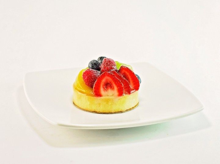 A small dessert with strawberries , raspberries , and blueberries on a white plate.