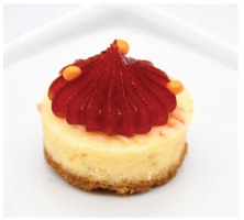 A small cheesecake with a red frosting on top
