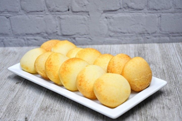 A white plate topped with bread balls on a wooden table.