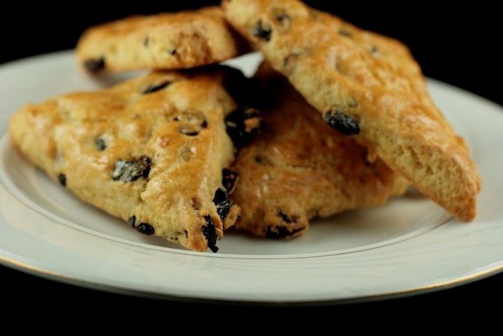 A white plate topped with raisin scones on a black background.