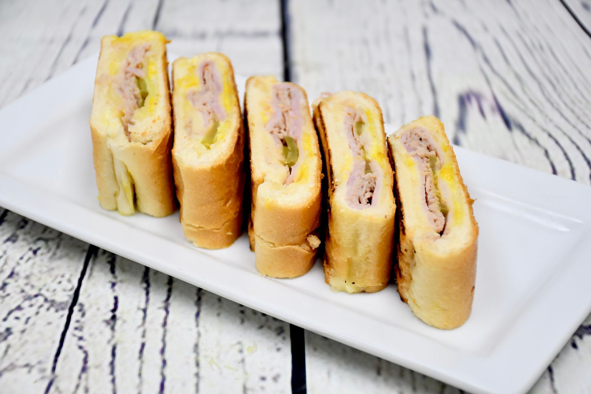 A white plate topped with sandwiches on a wooden table.