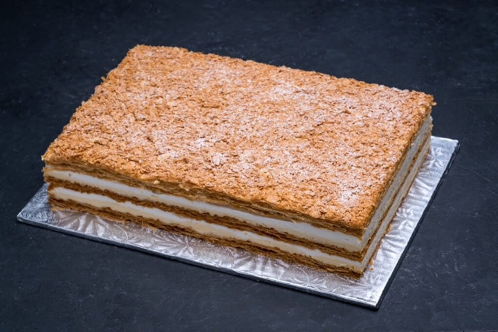 A large piece of cake is sitting on a silver plate on a table.