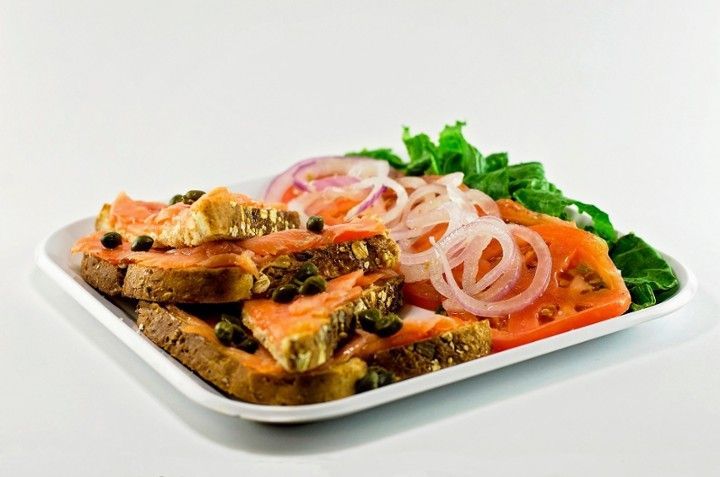 A white plate topped with sandwiches , tomatoes , onions and lettuce.
