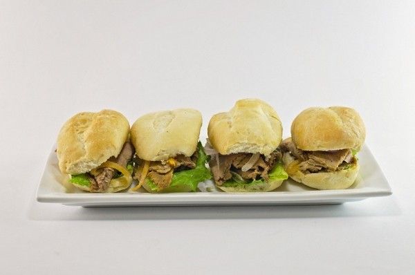 Four sandwiches are lined up on a white plate.