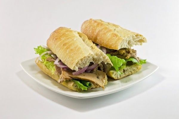 Two sub sandwiches on a white plate on a white background.