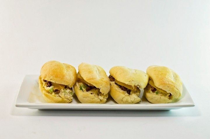 A white plate topped with four sandwiches on a white background.