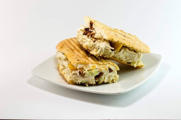 Two sandwiches are on a white plate on a white background.