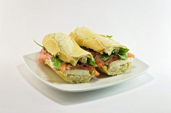 Two sub sandwiches on a white plate on a white background.