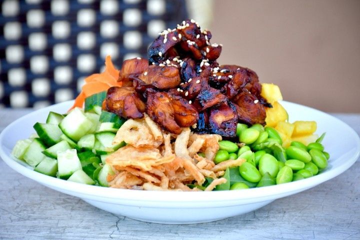 A bowl of food with meat and vegetables on a table.