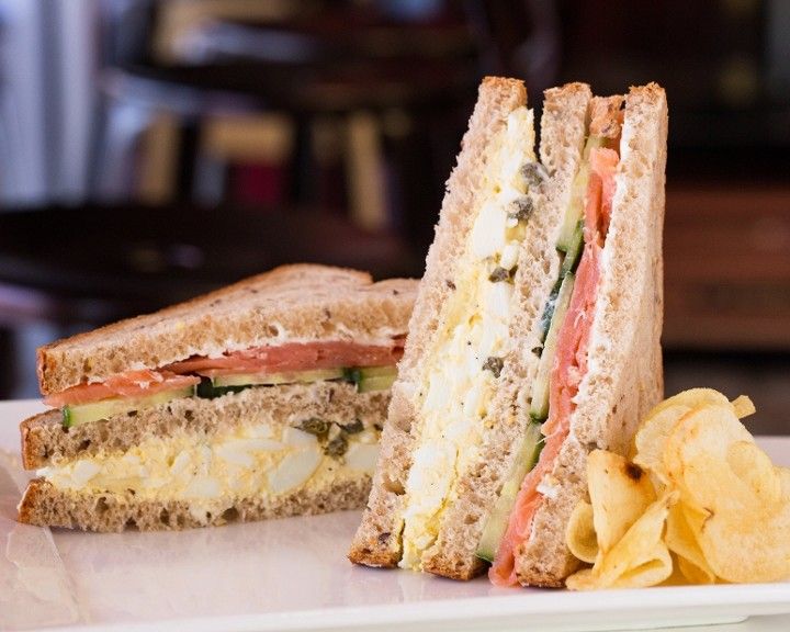 A club sandwich with potato chips on a white plate.