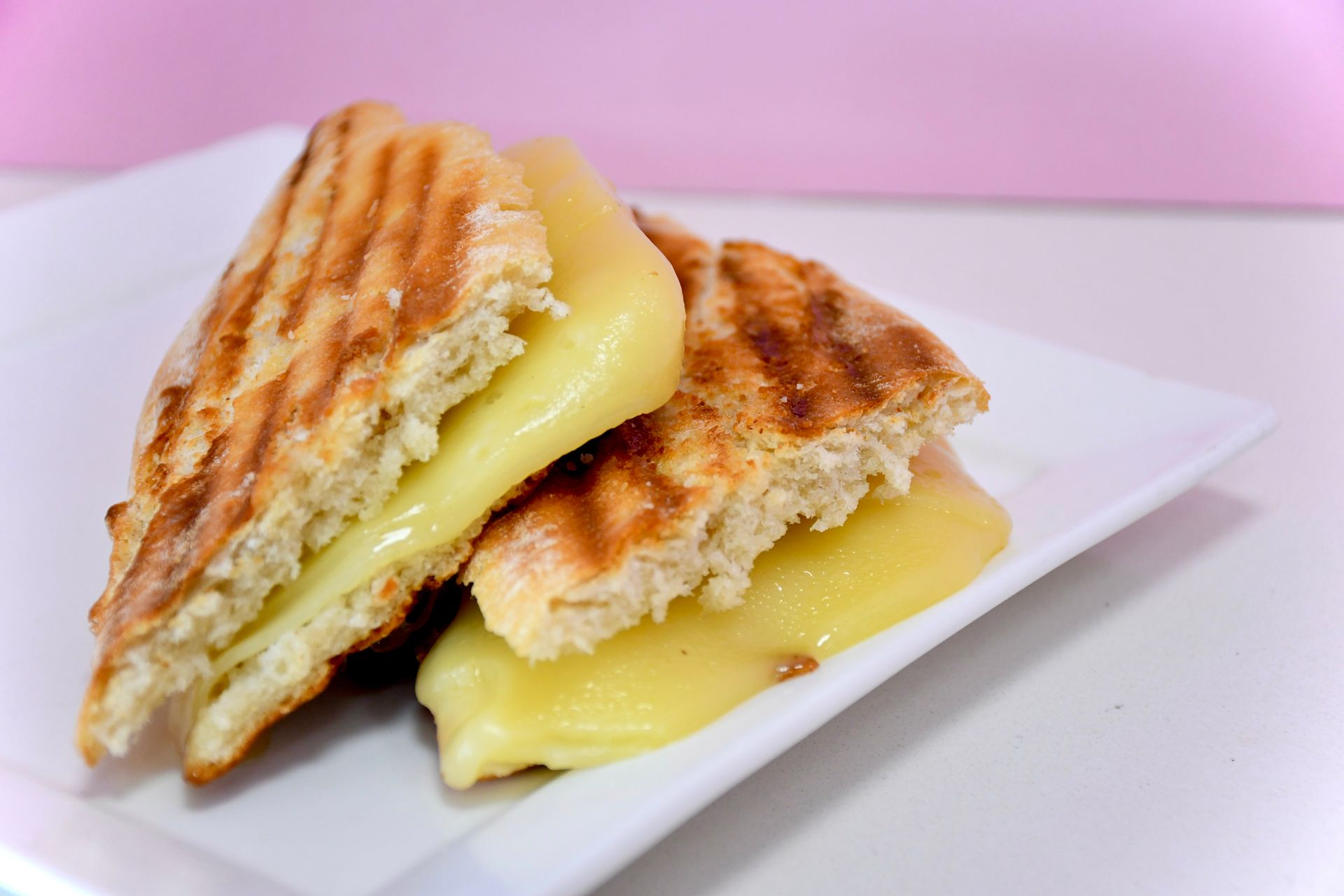 A grilled cheese sandwich is cut in half on a white plate.
