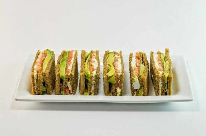 A white plate topped with a row of sandwiches.