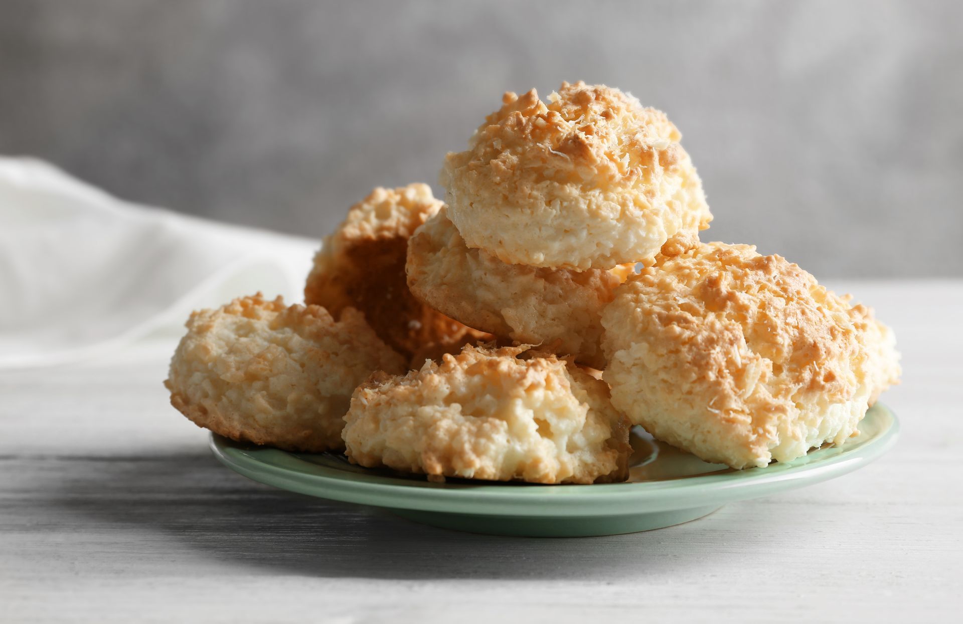 A green plate topped with coconut cookies on a table.
