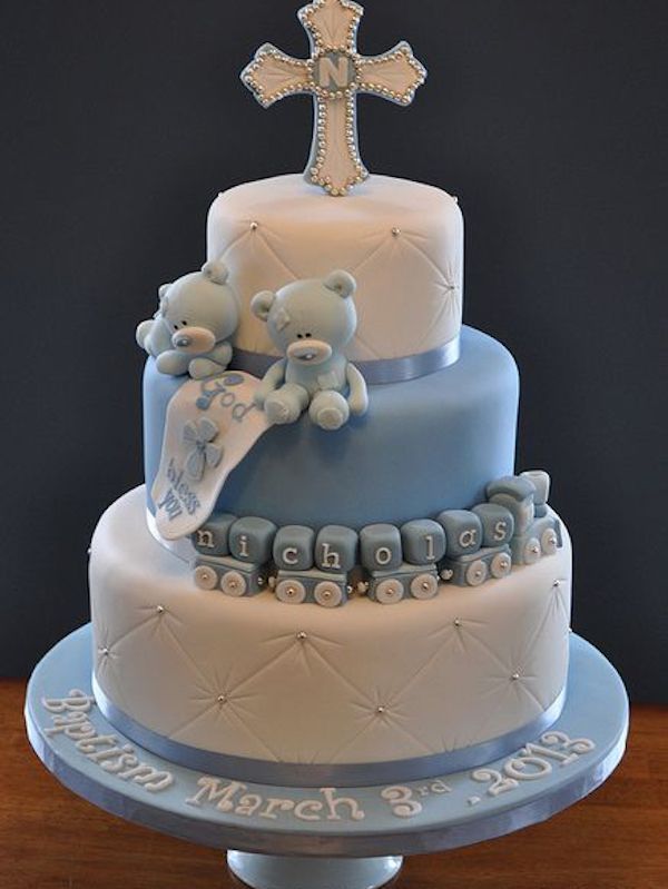 A blue and white cake with teddy bears and a cross on top