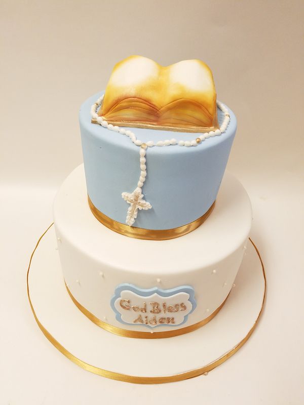 A blue and white cake with a rosary and a bible on top