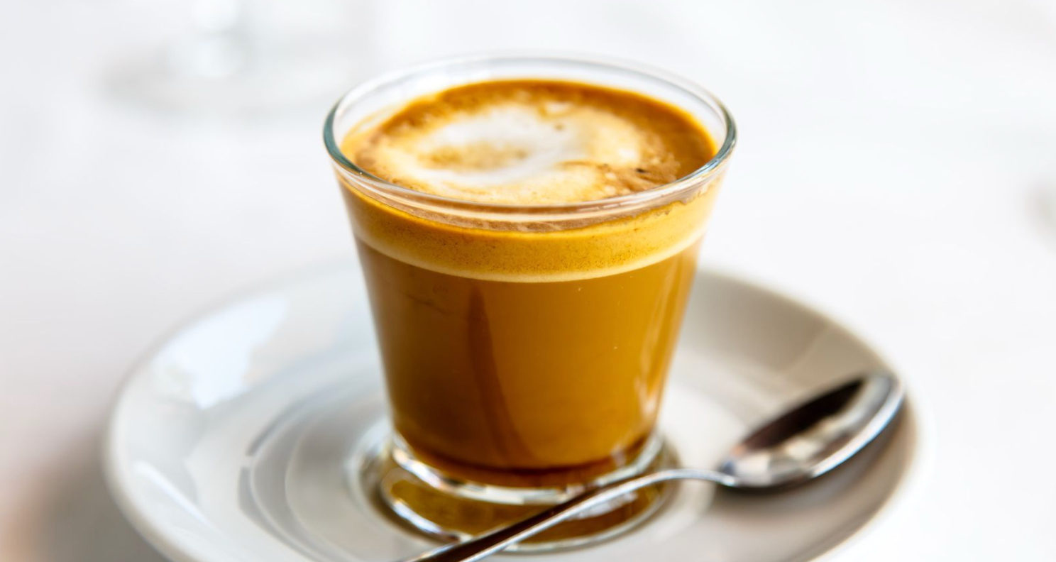 A cup of coffee on a saucer with a spoon