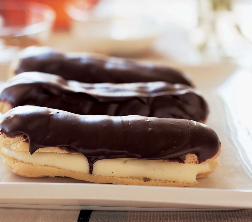 A row of chocolate covered pastries on a white plate