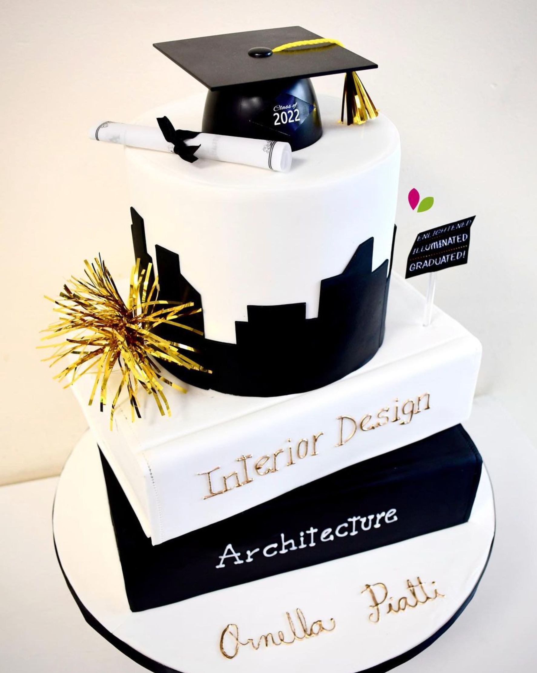 A black and white graduation cake with a graduation cap and diploma on top.
