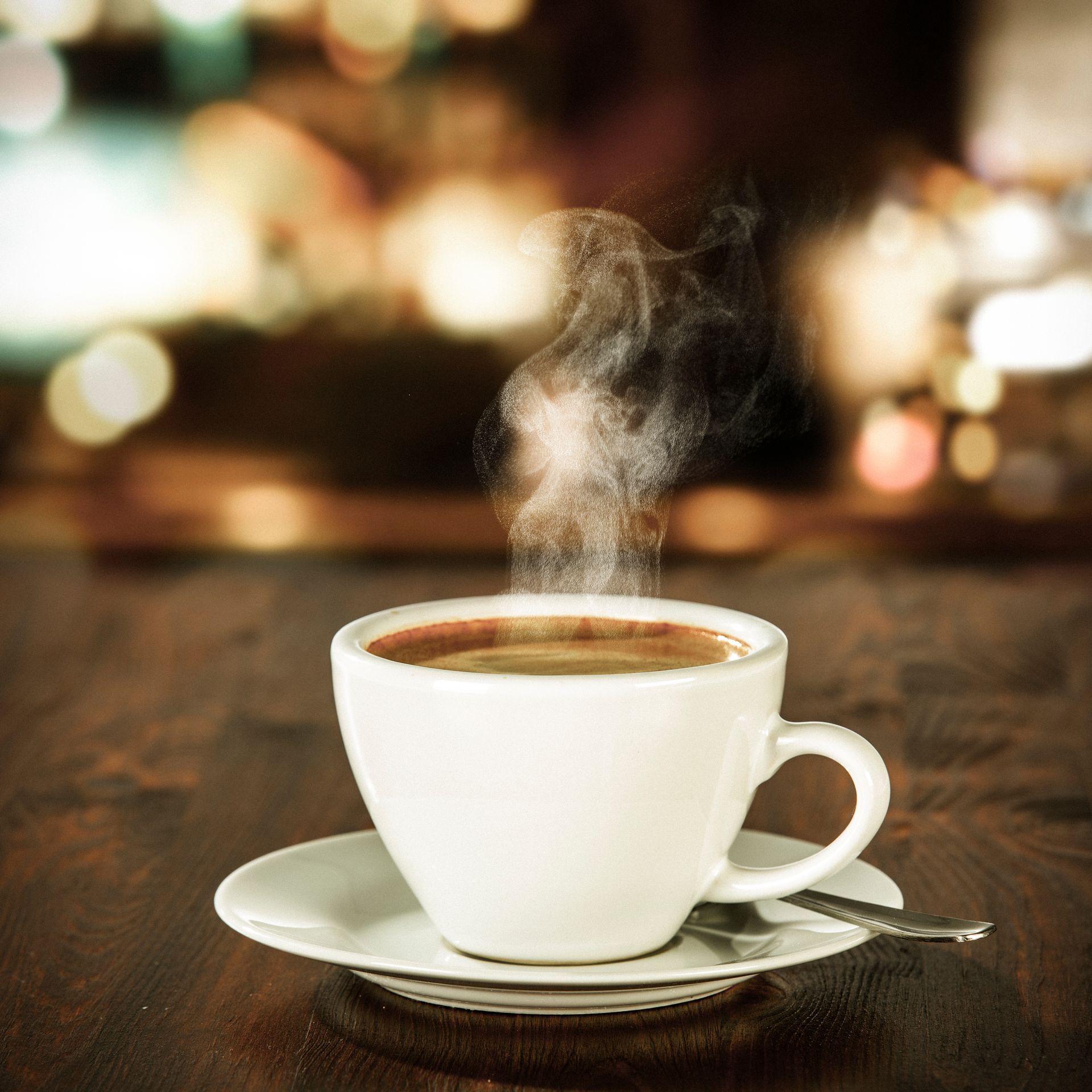 A cup of coffee on a saucer with steam coming out of it