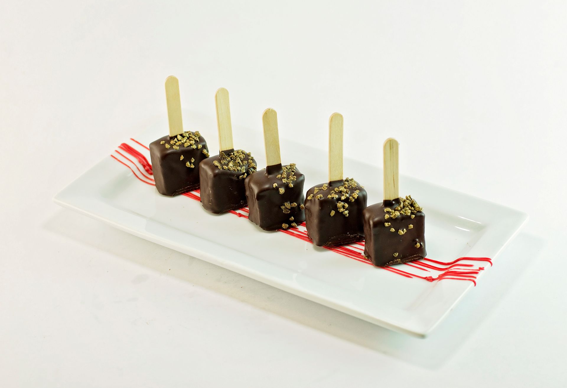 A white plate topped with chocolate cubes on sticks