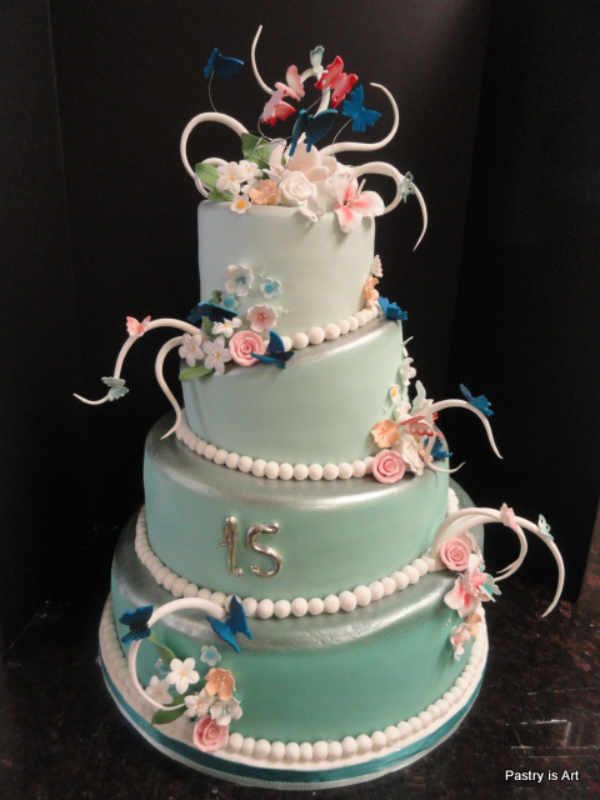 A cake with flowers and butterflies and the letter s on it