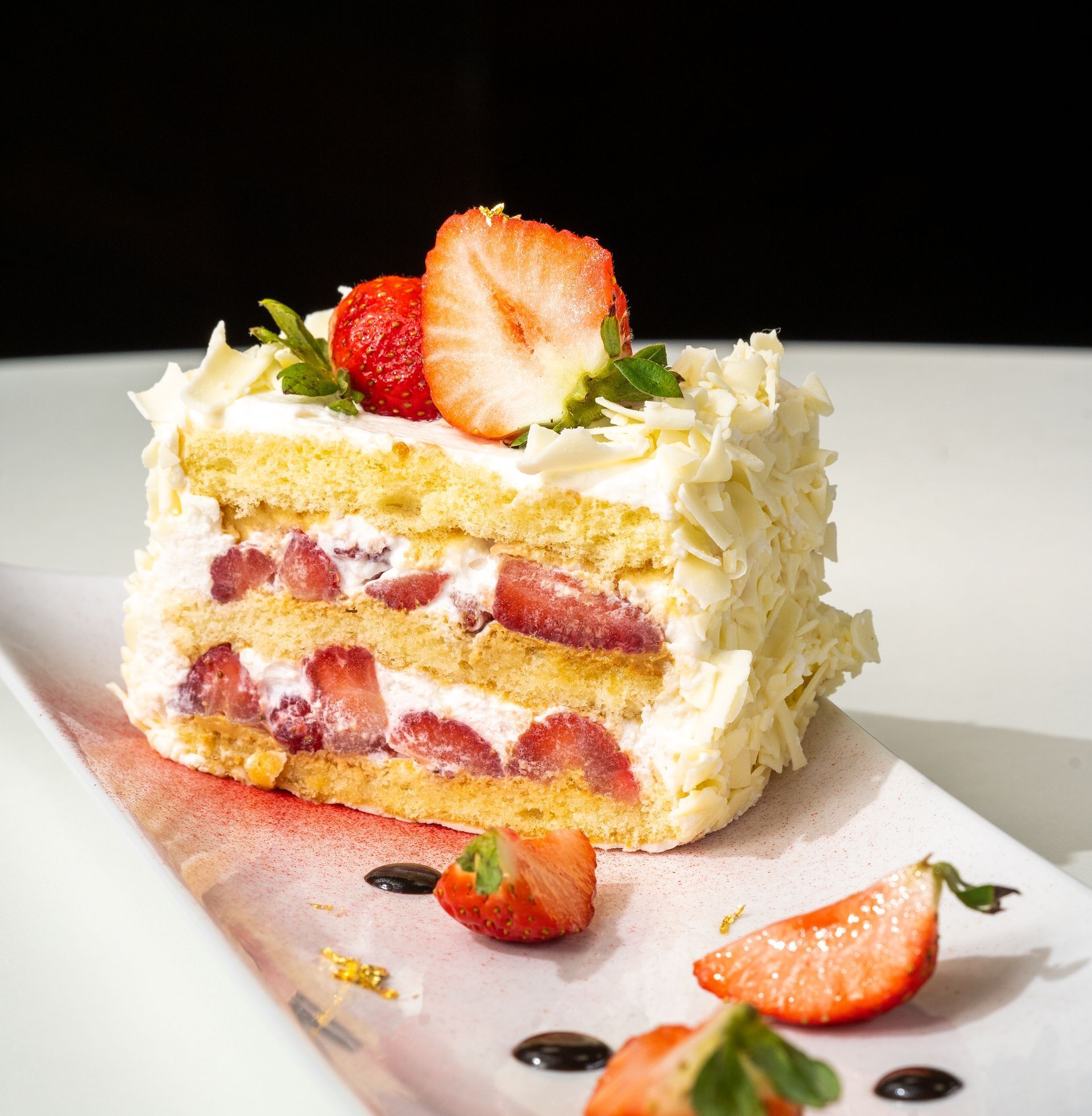 A slice of cake with strawberries on top on a white plate