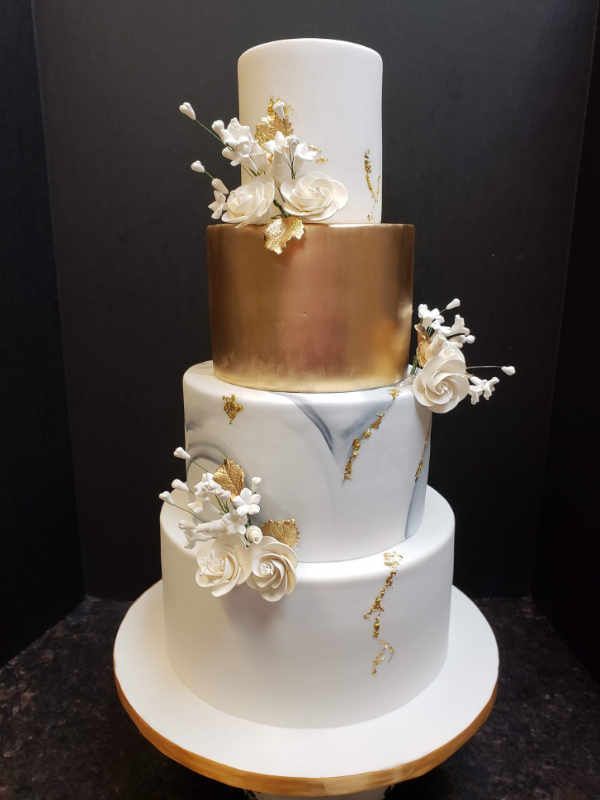 A white and gold wedding cake with flowers on it