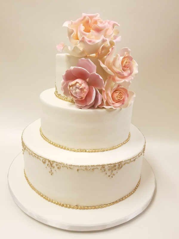 A white wedding cake with pink roses on top