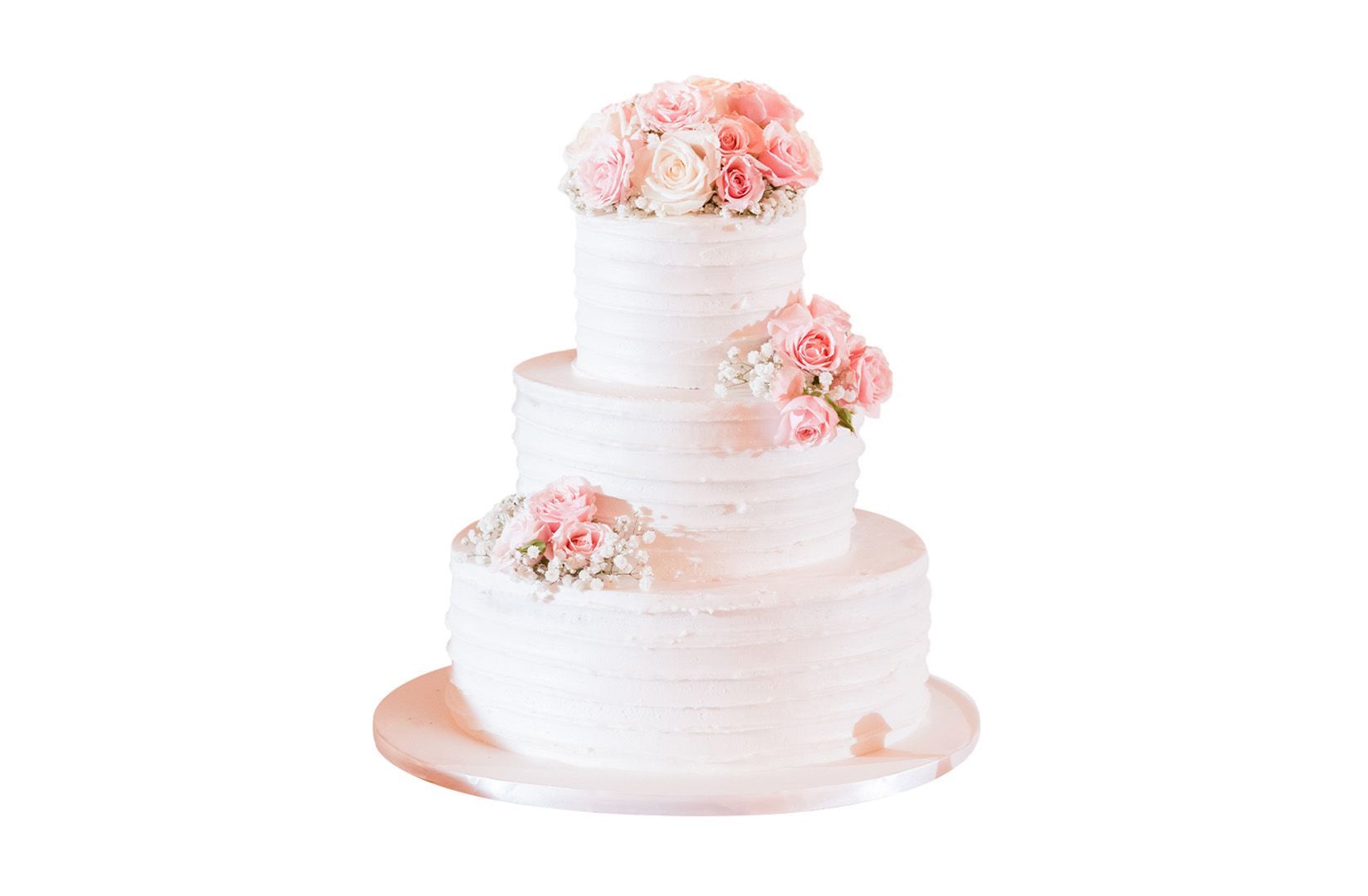 A white wedding cake with pink flowers on top on a white background.