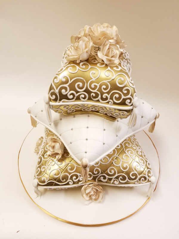 A stack of gold and white pillows sitting on top of each other on a plate.