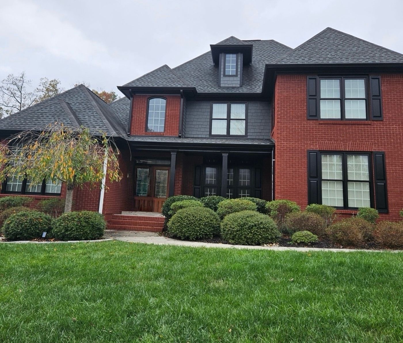 A large red brick house with a black roof and black shutters.