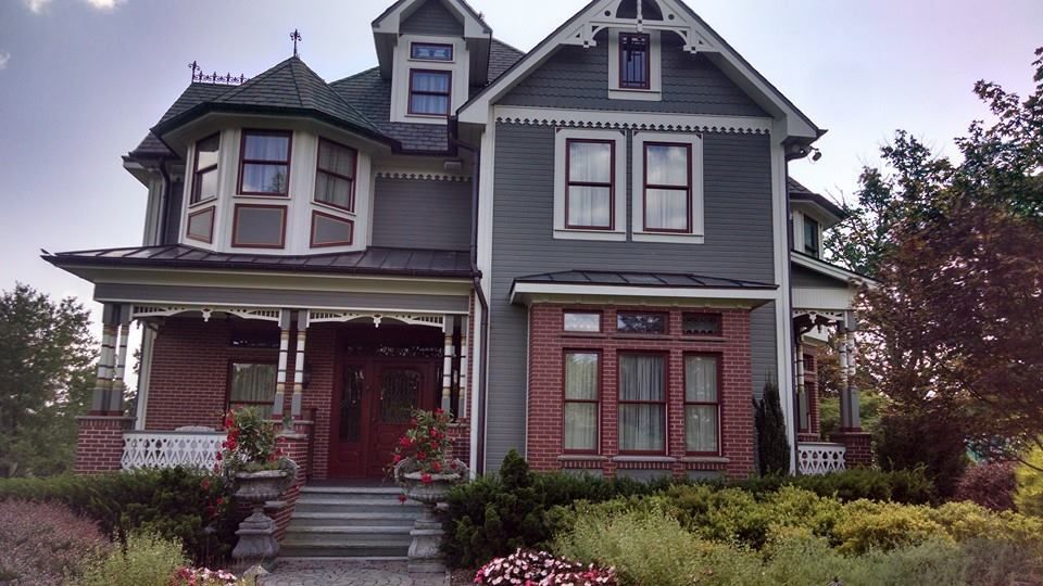 A large gray house with a red door and a large porch