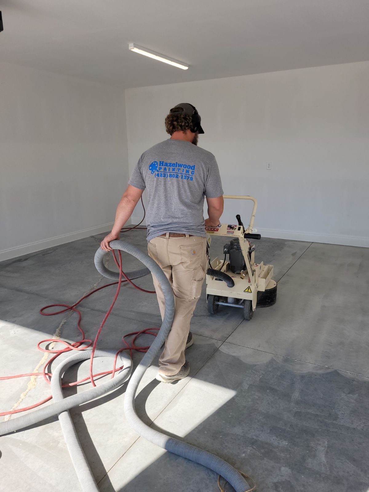 A man is using a vacuum cleaner to clean a concrete floor in a garage.