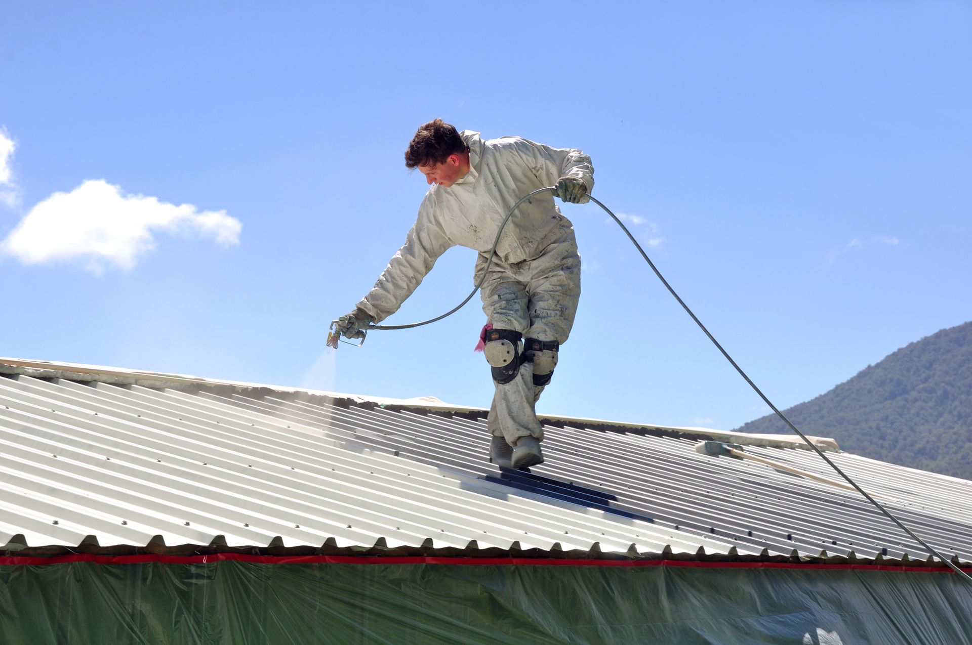 A man is spraying paint on the roof of a building