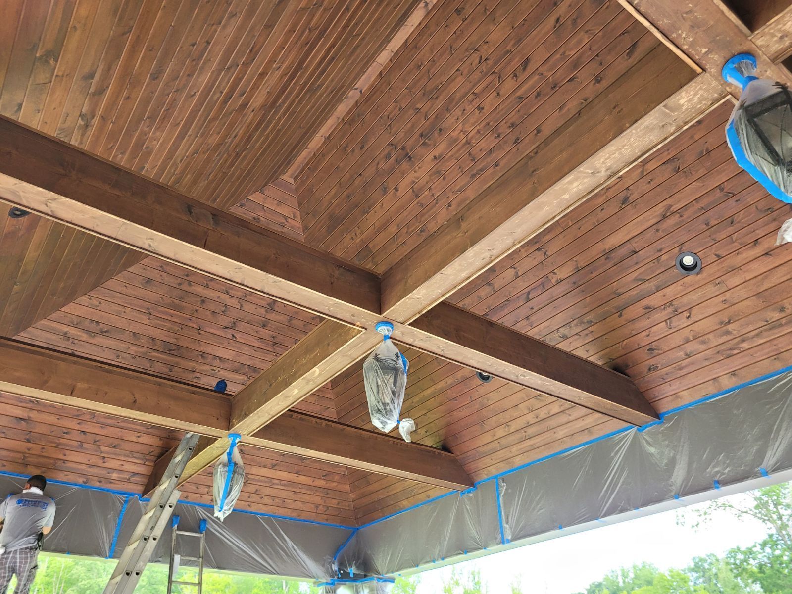 A man is painting the ceiling of a wooden structure.