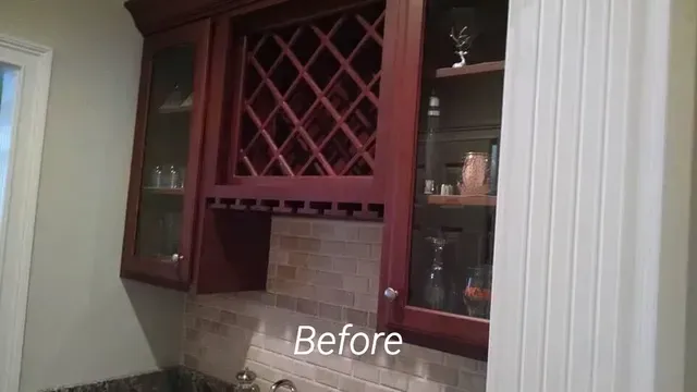 A before picture of a kitchen with wooden cabinets and a wine rack.