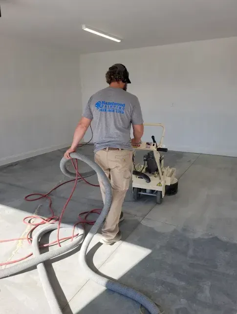 A man is using a vacuum cleaner to clean a concrete floor.