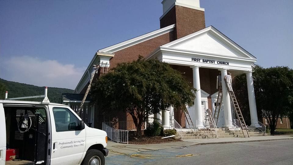 A white van is parked in front of a church that is being painted