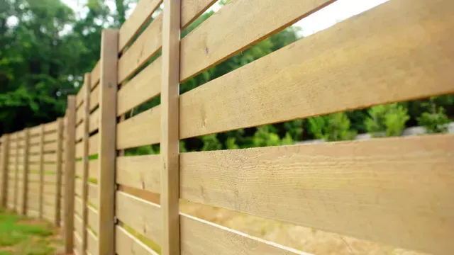 A close up of a wooden fence with trees in the background.