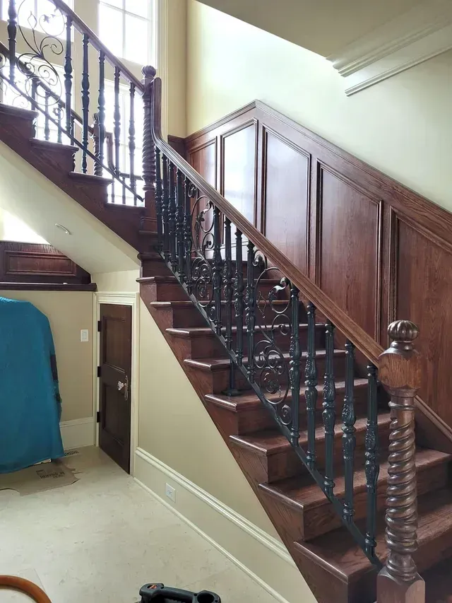 A wooden staircase with a wrought iron railing