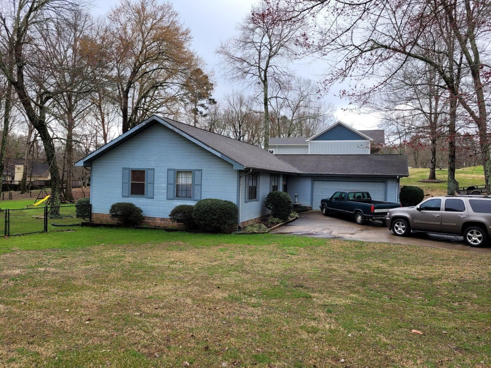 A blue house with two cars parked in front of it.